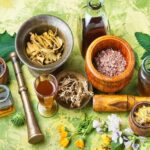 Various herbal medicines, including dried herbs, roots, and oils, displayed in wooden bowls and jars, along with a mortar and pestle on a textured green background.