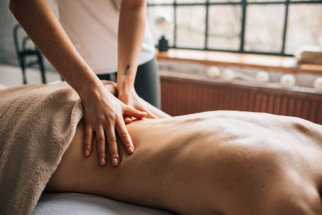 Person receiving a relaxing Ayurvedic oil massage therapy on the back in a calm spa setting with natural light.