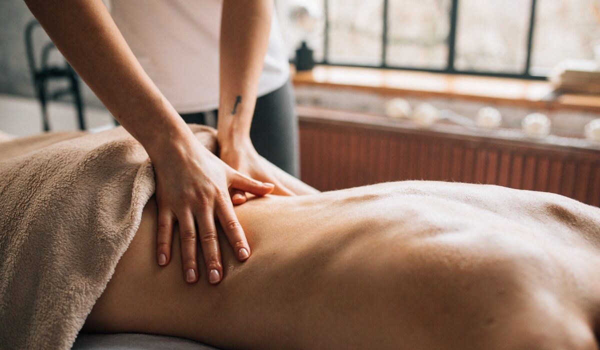 Person receiving a relaxing Ayurvedic oil massage therapy on the back in a calm spa setting with natural light.