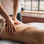 Person receiving a relaxing Ayurvedic oil massage therapy on the back in a calm spa setting with natural light.
